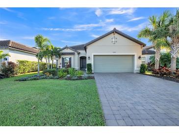 Single-story home with landscaped yard, paver driveway, and two-car garage at 12826 Sorrento Way, Bradenton, FL 34211