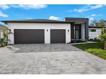 Modern two-car garage home with gray paver driveway and landscaping at 13377 Alocasia Ln, Port Charlotte, FL 33981