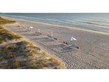 Relaxing beach with lounge chairs and umbrellas at 1465 Gulf Of Mexico Dr # 402, Longboat Key, FL 34228