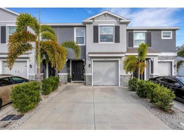 Two-story townhome with gray siding, two-car garage, and palm trees at 2471 Midnight Pearl Dr, Sarasota, FL 34240