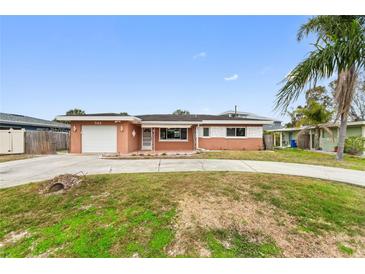 Ranch-style home with a large driveway and mature landscaping at 542 Baywood S Dr, Dunedin, FL 34698