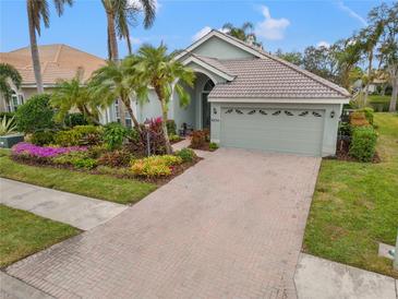 Landscaped home exterior with brick driveway and palm trees at 6234 Sturbridge Ct, Sarasota, FL 34238