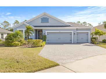 Gray house with two-car garage, landscaping, and paved driveway at 12556 Ryegrass Loop, Parrish, FL 34219