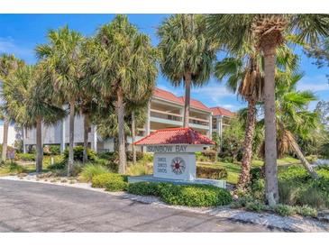 Sunbow Bay condo building with red tile roofs, balconies, and lush landscaping at 3801 E Bay Dr # 209, Holmes Beach, FL 34217