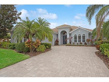 Single-story home with paver driveway, lush landscaping, and palm trees at 7019 Vilamoura Pl, Lakewood Ranch, FL 34202