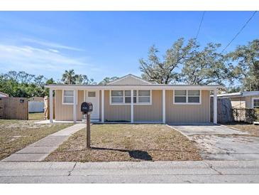 Tan house with a covered porch and a well-maintained lawn at 1518 Ewing Ave, Clearwater, FL 33756