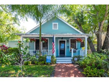 Charming light blue cottage with a white picket fence and lush landscaping at 321 27Th W St, Bradenton, FL 34205