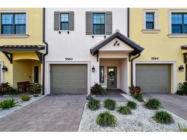 Townhome exterior showcasing gray garage doors, and well-manicured landscaping at 5560 Cannes Cir # 3-106, Sarasota, FL 34231