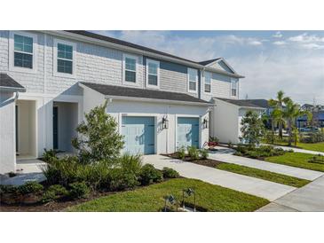 Three-unit townhome building with light gray siding, light blue garage doors, and landscaping at 8684 Canyon Creek Trl, Parrish, FL 34219