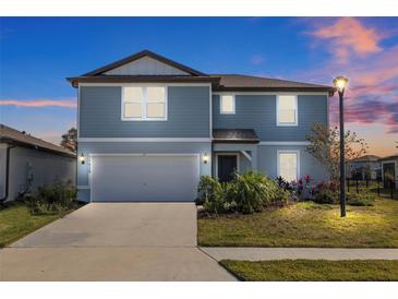 Two-story house with gray siding, attached garage, and landscaping at 11628 Middle Fork Way, Parrish, FL 34219