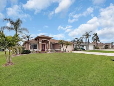 Single-story home with a red door, landscaped lawn, and palm trees at 25067 Palisade Rd, Punta Gorda, FL 33983
