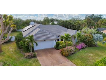 Single-story home with grey tile roof, solar panels, and lush landscaping at 5179 Flicker Field Cir, Sarasota, FL 34231