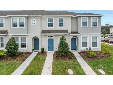 Three-unit townhome building with gray siding, blue doors, and landscaping at 6111 Fairmont Ln, Palmetto, FL 34221