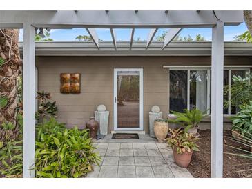 Inviting front entrance with pergola, lush landscaping, and decorative pots at 6231 Beechwood Ave, Sarasota, FL 34231