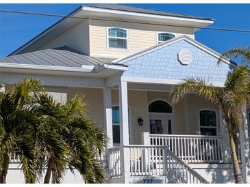 Two-story house with light yellow walls, blue accents, and a metal roof at 727 Holly Rd, Anna Maria, FL 34216