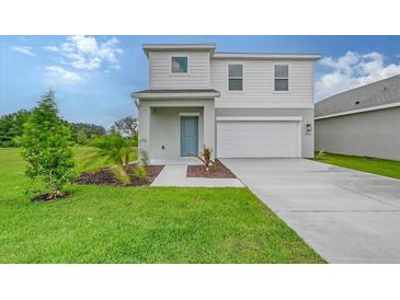 Two-story house with light gray siding, a two-car garage, and a landscaped lawn at 13115 Cedar Elm Lane, Parrish, FL 34219