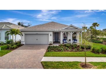 One-story home with gray siding, a covered porch, and a landscaped yard at 25042 Coquina Ridge Way, Englewood, FL 34223