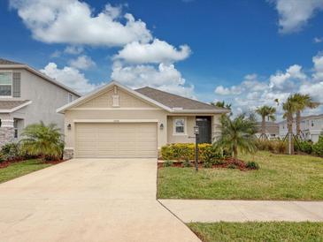 Tan house with a two-car garage and landscaped lawn at 3206 Hilltop Cir, Bradenton, FL 34211
