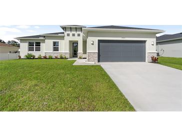 Single-story home with gray garage door and well-manicured lawn at 3425 Dryden St, North Port, FL 34288