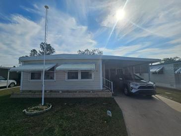Single-wide mobile home with carport and landscaping at 5619 Bayshore Rd # 115, Palmetto, FL 34221