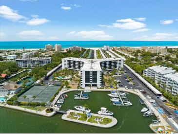 Aerial view of waterfront community with tennis courts, marina, and ocean access at 5855 Midnight Pass Rd # 311, Sarasota, FL 34242