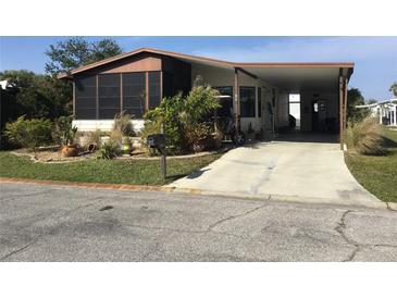 Single-wide manufactured home with carport, landscaped yard, and screened porch at 763 Lakeside Dr, North Port, FL 34287