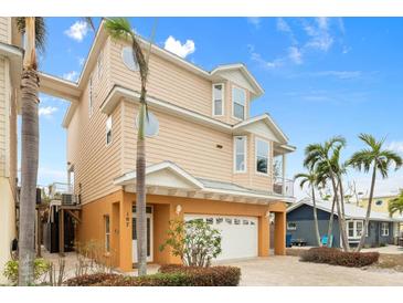 Tan three-story house with a white garage door and palm trees at 107 75Th St, Holmes Beach, FL 34217
