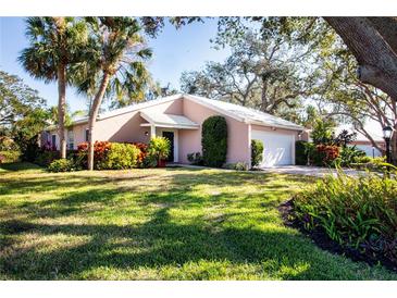 Light pink house with a white garage door and lush green lawn at 7213 Las Casas Dr, Sarasota, FL 34243