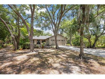 Tan house with gray garage doors and mature landscaping, long driveway at 7408 Oak Run Ln, Sarasota, FL 34243