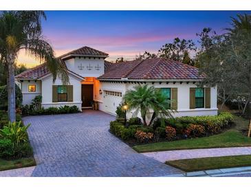 Luxury home with brick driveway, palm trees, and landscaped yard at 7504 Windy Hill Cv, Lakewood Ranch, FL 34202