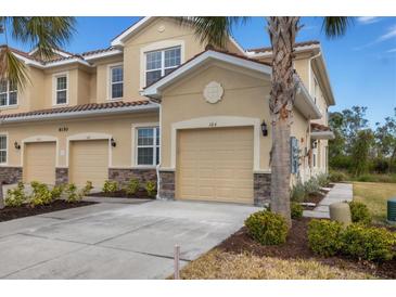 Tan two-story condo building with attached garage and landscaping at 8150 Enclave Way # 104, Sarasota, FL 34243