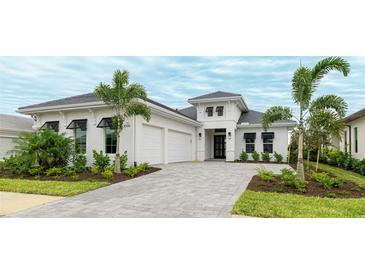 Beautiful home featuring white stucco, black window awnings, two-car garage, paved driveway and manicured landscaping at 8376 Sea Glass Ct, Sarasota, FL 34240