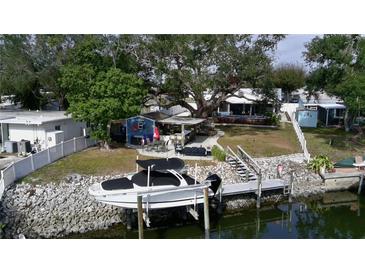 Aerial view of waterfront home with boat dock, tiki bar, and lush landscaping at 1006 69Th W Ave, Bradenton, FL 34207