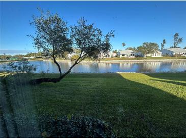 Scenic view of a tranquil lake, lush green grass, and charming homes at 4869 Independence Dr # 4869, Bradenton, FL 34210