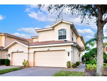 Two-story tan house with a two car garage, landscaping and a tree in front at 7022 Prosperity Cir # 801, Sarasota, FL 34238