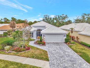 Single-story home with gray tile roof, white garage door, and landscaped yard at 230 Vestavia Dr, Venice, FL 34292
