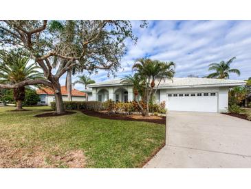 Single-story home with a white exterior, landscaped yard, and a two-car garage at 8303 Deerbrook Cir, Sarasota, FL 34238
