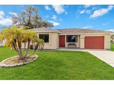 Single story home with red garage door and landscaped lawn at 20096 Tappan Zee Dr, Port Charlotte, FL 33952