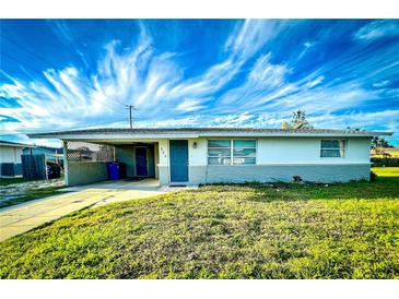 Ranch-style home features carport, and a well-manicured lawn at 360 Flamingo Rd, Venice, FL 34293