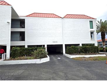 Exterior view of condo building with parking garage and landscaping at 3805 E Bay Dr # 302, Holmes Beach, FL 34217