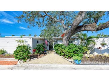 Charming single-story home with lush landscaping and a large tree in the front yard at 6005 Midnight Pass Rd # N8, Sarasota, FL 34242