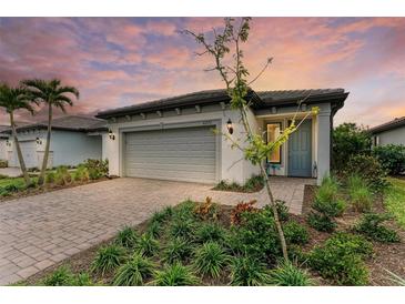 Single-story home with gray garage door, landscaping, and paver driveway at 6273 Winding Pine Dr, Nokomis, FL 34275
