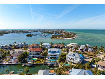 Stunning aerial view of waterfront home with pool, dock, and boat lift in a beautiful coastal community at 718 Key Royale Dr, Holmes Beach, FL 34217