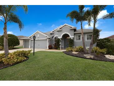 Gray house with two-car garage, landscaping, and palm trees at 5383 Creekside Trl, Sarasota, FL 34243