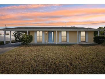 Single story home with light yellow exterior, blue door, and landscaped lawn at 6380 S Biscayne Dr, North Port, FL 34287