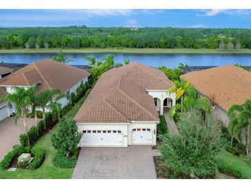 Single-Gathering home with two-car garage, situated on a lake with lush landscaping at 7220 Whittlebury Trl, Lakewood Ranch, FL 34202
