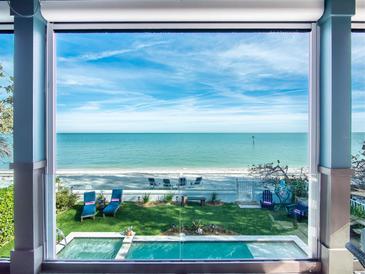 Serene beach view from home with a pristine pool and a well-manicured lawn with beach access at 915 N Shore Dr, Anna Maria, FL 34216