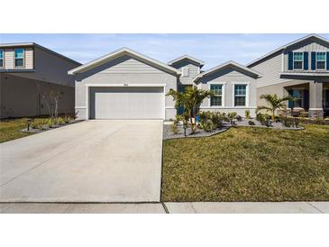 Single-story home with gray siding, two-car garage, and landscaped lawn at 9810 Eventide Trl, Parrish, FL 34219
