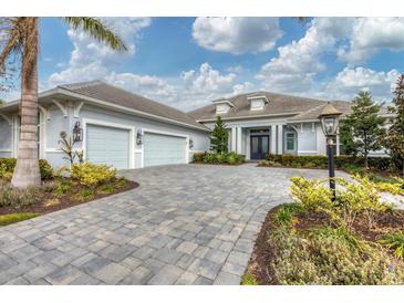 Two-story home with light blue exterior, gray paver driveway and landscaping at 16007 Castle Park Ter, Lakewood Ranch, FL 34202