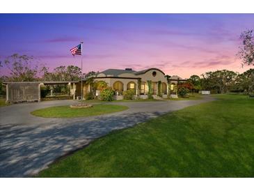 Spanish style home with circular driveway, landscaping and flag at 11701 Marsh Head Road, Sarasota, FL 34240